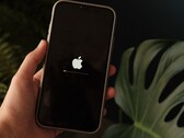 Ręka trzyma iPhone’a, a na ekranie widoczne są logo Apple oraz pasek postępu.