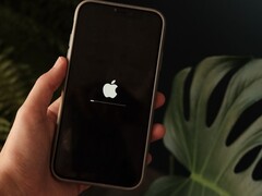 Ręka trzyma iPhone’a, a na ekranie widoczne są logo Apple oraz pasek postępu.