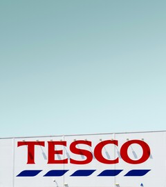 Zewnętrzne oznakowanie Tesco sfotografowane na tle czystego nieba (źródło zdjęcia: Simone Hutsch via Unsplash)