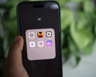 Dłoń trzyma smartfon, na którym widoczny jest folder o nazwie „AI” zawierający aplikacje, w tym Gemini, ChatGPT i Claude