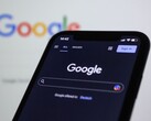 Smartfon wyświetlający stronę wyszukiwarki Google na tle ekranu z logo Google