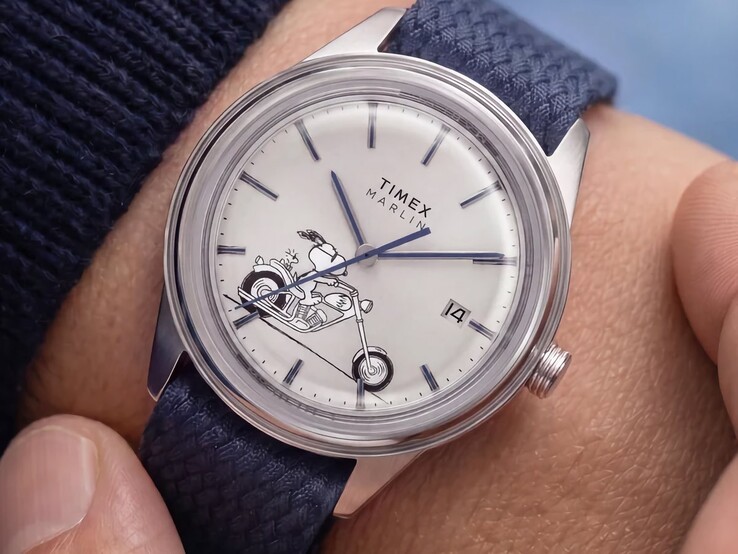 Zegarek Peanuts x Timex Marlin Jet Automatic Easy Rider noszony na nadgarstku, przedstawiający Snoopy’ego jadącego na motocyklu na srebrno-białej tarczy, z niebieskimi znacznikami i wskazówkami oraz niebieskim paskiem z tkaniny.