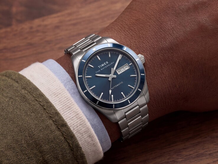 Zegarek Timex Waterbury Heritage Automatic z niebieską emaliowaną tarczą noszony na nadgarstku, ukazujący srebrzystą kopertę i bransoletę ze stali nierdzewnej.