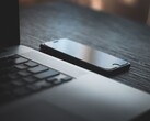 Smartfon leżący obok otwartego laptopa na ciemnym biurku