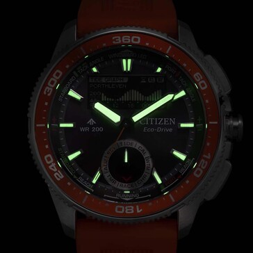 Zdjęcie Citizen Promaster Wave Tracker JV3000-13E przy słabym oświetleniu, pokazujące świecące wskazówki i znaczniki godzin na ciemnym tle.