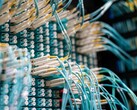 Niebieskie kable światłowodowe z białymi złączami podłączone do panelu krosowego w centrum danych