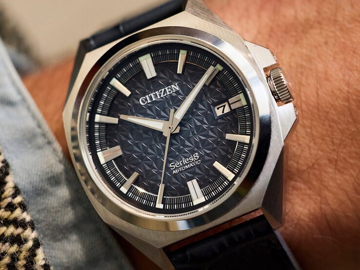 Zegarek automatyczny Citizen Series 8 831 z tarczą w geometryczne wzory w kolorze spalonej pomarańczy i brązu, kopertą i ramką w odcieniu złota oraz zintegrowaną bransoletą typu H-link w odcieniu złota, noszony na nadgarstku.