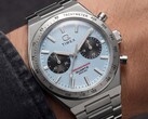 Zbliżenie na zegarek Timex Q Timex Continental Chronograph TW2Y92400 noszony na nadgarstku, wyposażony w lodowoniebieską tarczę w stylu CD z promienistym wzorem, czarne tarcze pomocnicze, srebrną ramkę z tachymetrem oraz zintegrowaną bransoletę ze stali nierdzewnej.