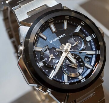 Zbliżenie na model Casio G-Shock GST-W1000AD-2A z niebieską tarczą, ukazujące układ trzech warstwowych tarcz pomocniczych, świecące znaczniki, srebrne wskazówki oraz czarną ramkę.