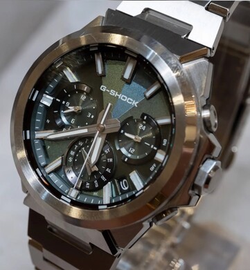 Zbliżenie na model Casio G-Shock GST-W1000D-3A z zieloną tarczą, ukazujące jej geometryczną fakturę, trzy tarcze pomocnicze, świecące znaczniki oraz polerowaną ramkę ze stali nierdzewnej.