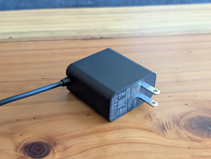 Zasilacz sieciowy USB-C o mocy 65 W, dostarczany wraz z laptopem Lenovo Yoga Slim 7 14. Proszę zwrócić uwagę na niewysuwane wtyczki sieciowe oraz zintegrowany kabel USB-C po drugiej stronie