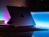 Półotwarty MacBook w ciemnym pokoju, światło wylewające się przez szczelinę na biurko
