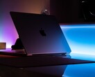 Półotwarty MacBook w ciemnym pokoju, światło wylewające się przez szczelinę na biurko