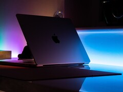 Półotwarty MacBook w ciemnym pokoju, światło wylewające się przez szczelinę na biurko