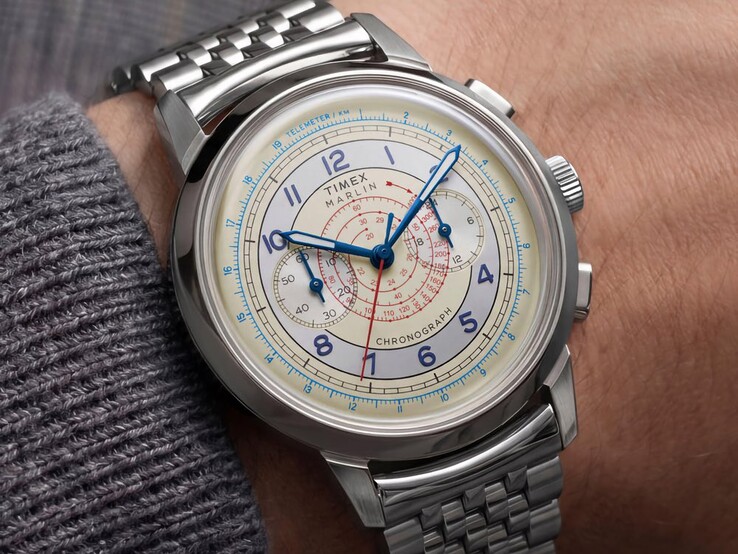 Chronograf Timex Marlin Neo Classic z kremową tarczą, niebieskimi wskazówkami i bransoletą ze stali nierdzewnej noszony na nadgarstku.