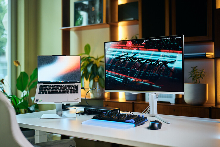 Kompletna konfiguracja stanowiska roboczego obejmująca laptop ThinkPad X9 14 na podstawce, kartę graficzną eGPU Aorus RTX 5060 Ti AI Box oraz zewnętrzny monitor, na którym wyświetlana jest gra Cyberpunk 2077.