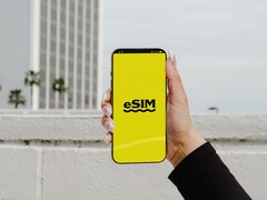 Dłoń trzymająca smartfon z dużym napisem „eSIM” na żółtym ekranie.