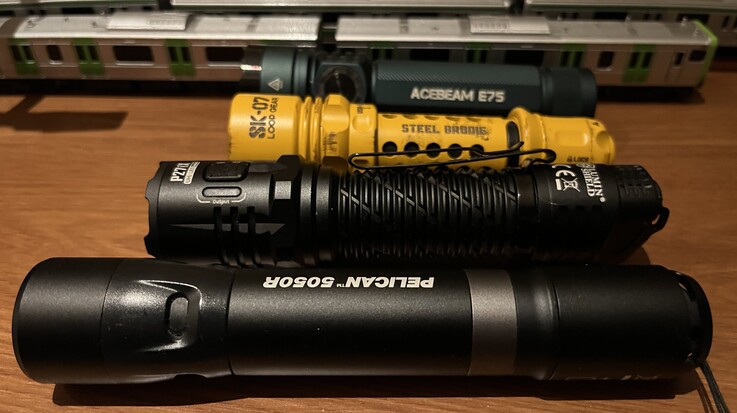 Żółta latarka SK-07 firmy Loop Gear w porównaniu z modelami Acebeam E75 (z tyłu), Nitecore P27i oraz Pelican 5050R