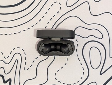 Bezprzewodowe słuchawki douszne Status Pro X w etui ładującym.