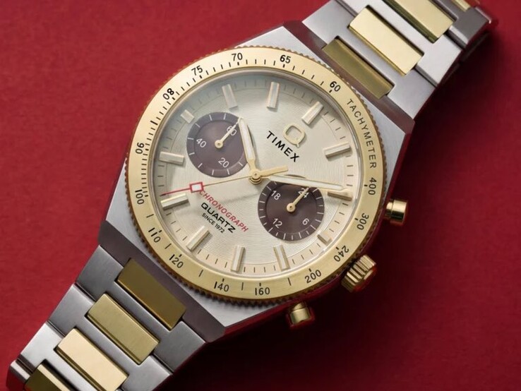 Zbliżenie na zegarek Timex Q Timex Continental Chronograph TW2Y92300 noszony na nadgarstku, ukazujące jego złocistą tarczę, brązowe tarcze pomocnicze, pierścień z tachymetrem oraz dwukolorową bransoletę ze stali nierdzewnej.