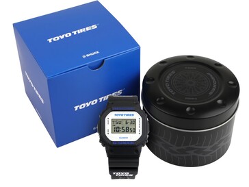 Zegarek Casio G-Shock DW5600TT25-1 prezentowany z niebieskim pudełkiem Toyo Tires i niestandardową metalową puszką.
