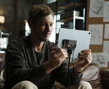 Użytkownik podłączający przezroczysty przenośny dysk SSD Sharge Disk Pro z aktywnym chłodzeniem do tabletu za pomocą kabla USB-C. (Sharge via Kickstarter)