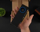 Osoba trzymająca niskoprofilowy procesor graficzny Intel Arc Pro B50 do stacji roboczych z chłodnicą w stylu dmuchawy, pokazany na tle opakowania. (Źródło zdjęcia: ETA Prime via YouTube)