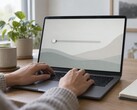 Ręce na klawiaturze laptopa, suwak po lewej stronie ekranu