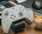 Biały kontroler Xbox spoczywający na drewnianym biurku obok małej figurki kota (źródło zdjęcia: FOX ^.ᆽ.^= ∫ via Pexels)