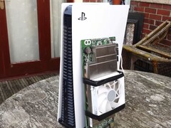 Konsola PlayStation 5 umieszczona obok niestandardowej płyty AMD BC250 z radiatorem i wentylatorem chłodzącym. (Źródło zdjęcia: Budget-Builds Official via YouTube)